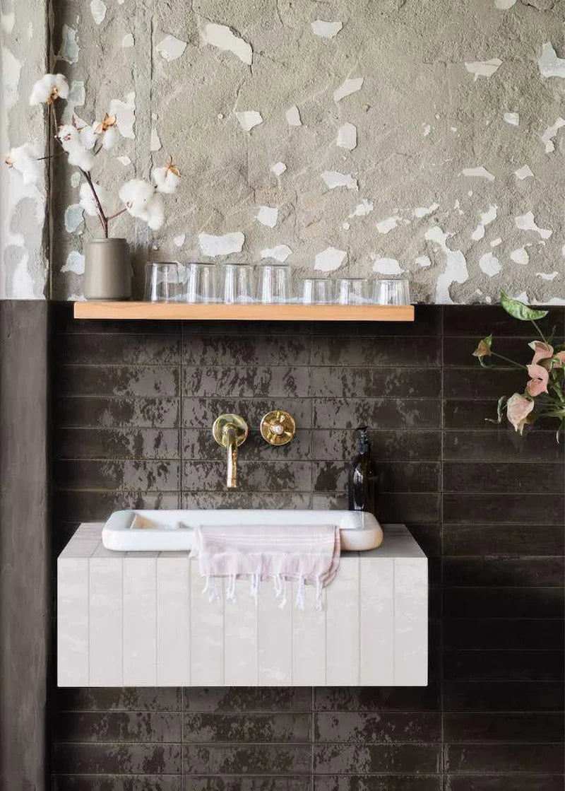 rustic and distressed bathroom wall combining exposed cement and black glossy subway tiles