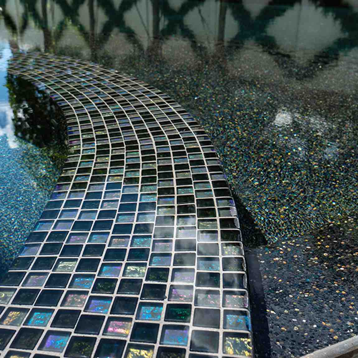 Iridescent Clear Glass Pool Tile Dark Blend 1''x1'' featured on a dark black swimming pools