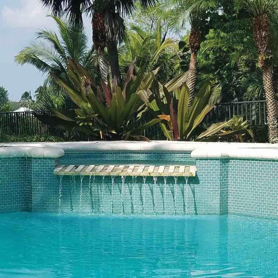 Swimming pool waterfall featuring iridescent glass tiles in aqua color